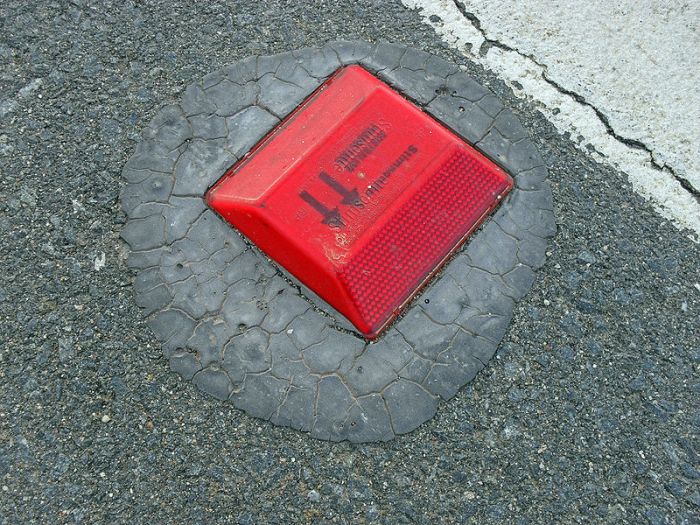 You see red raised roadway markers in the road ahead.